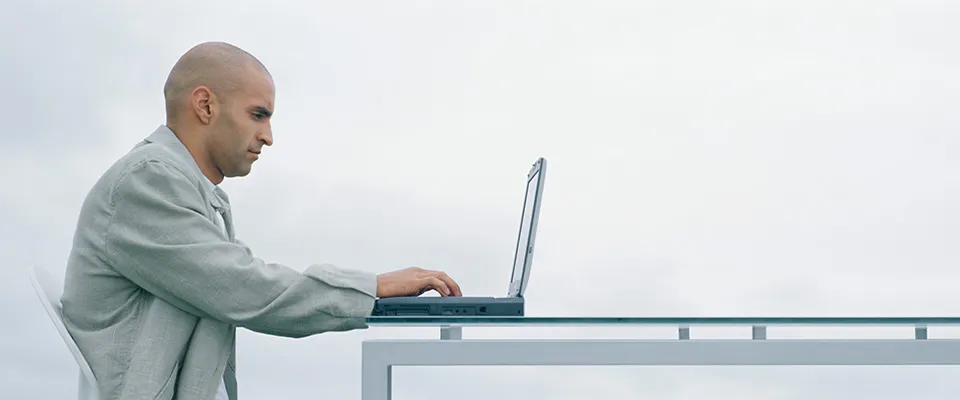 Mann sitzt auf einer Couch und arbeitet am Laptop